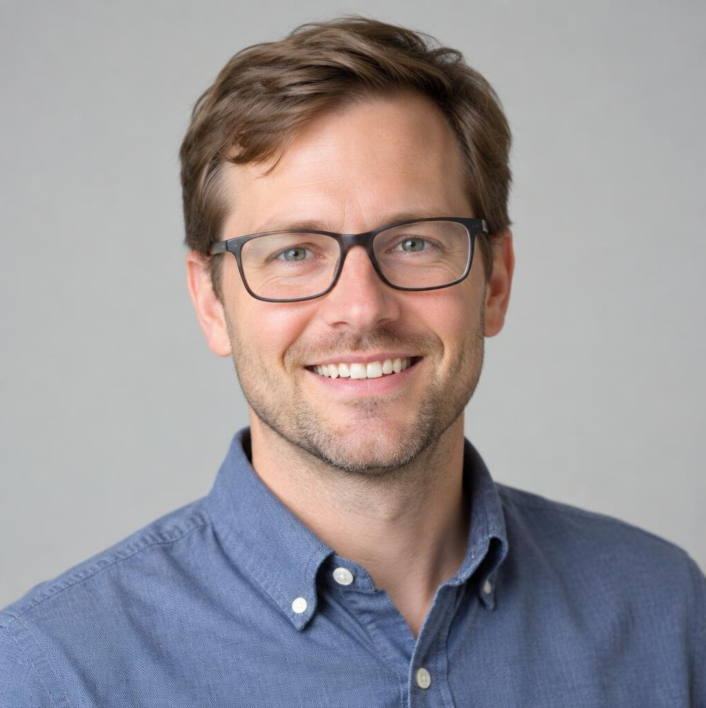 Portrait of a man with glasses smiling in a casual shirt