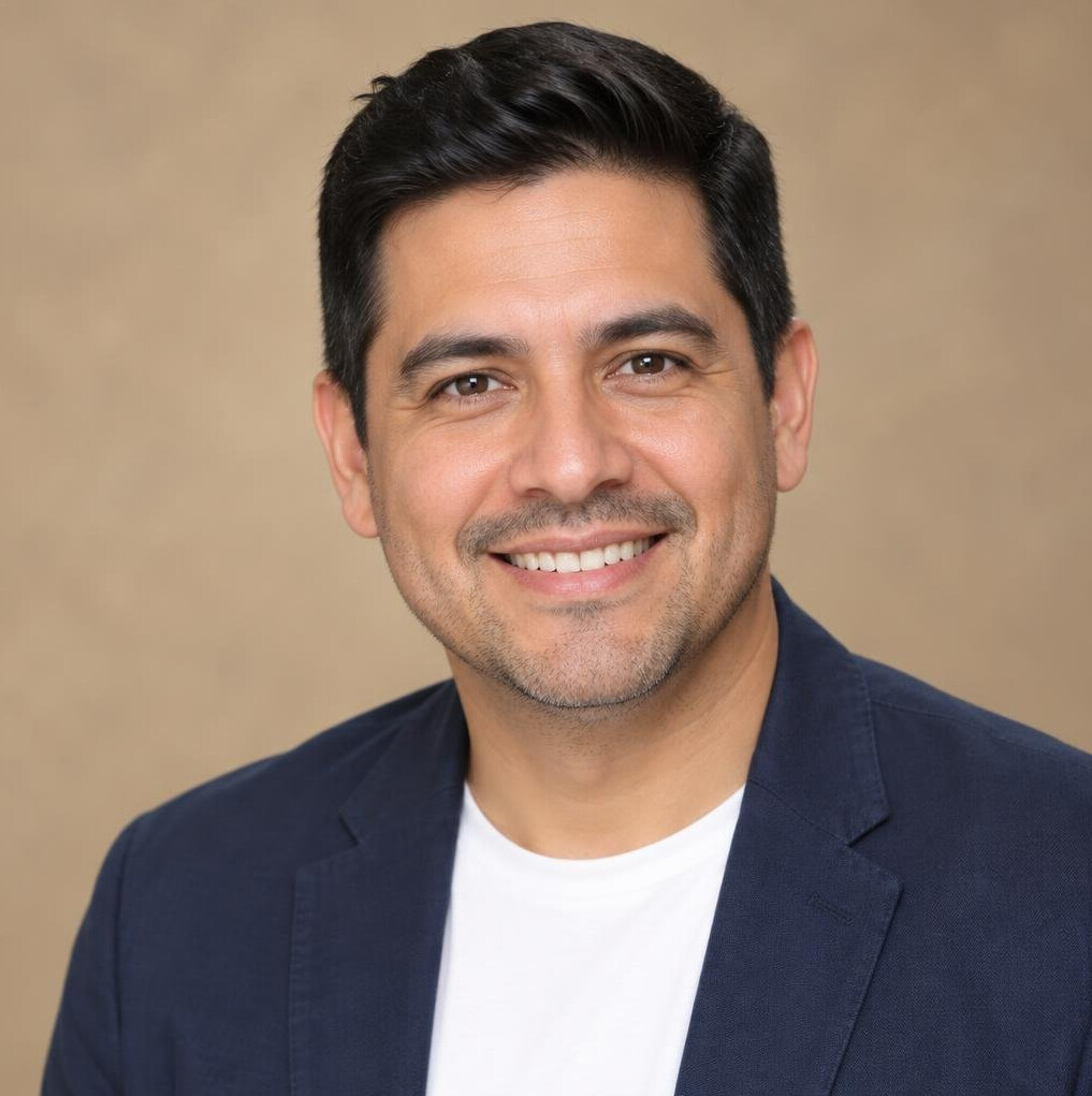 Studio portrait of a Hispanic man smiling in a casual blazer