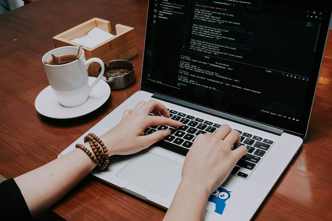 programmer writing code on laptop
